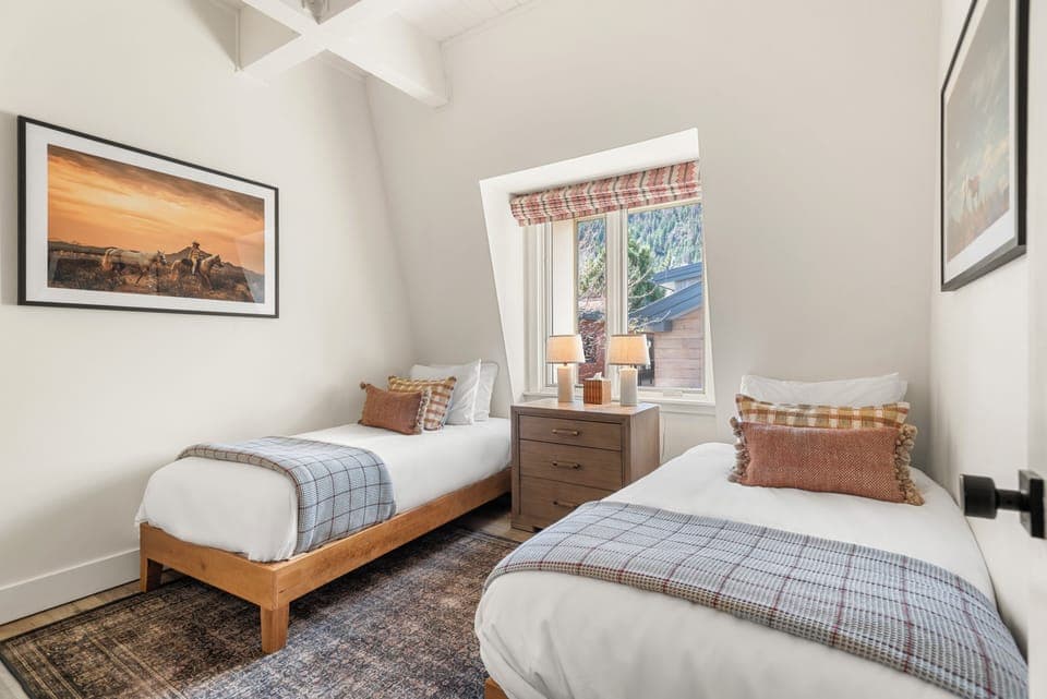 Guest bedroom with two twin beds, closet, Aspen Mountain views, and shared bathroom.