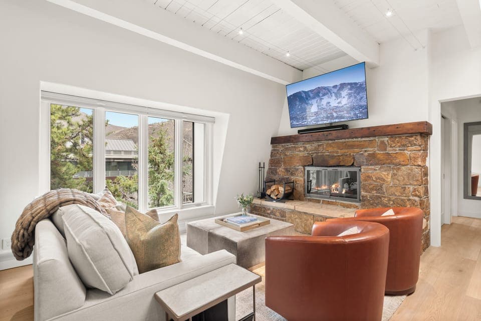 Top-floor sanctuary at Chateau Dumont. This living room features a 65" smart TV with Xfinity cable and Roku Streaming, queen-sized pull out couch, wood-burning fireplace, views of Smuggler and Red Mountain.
