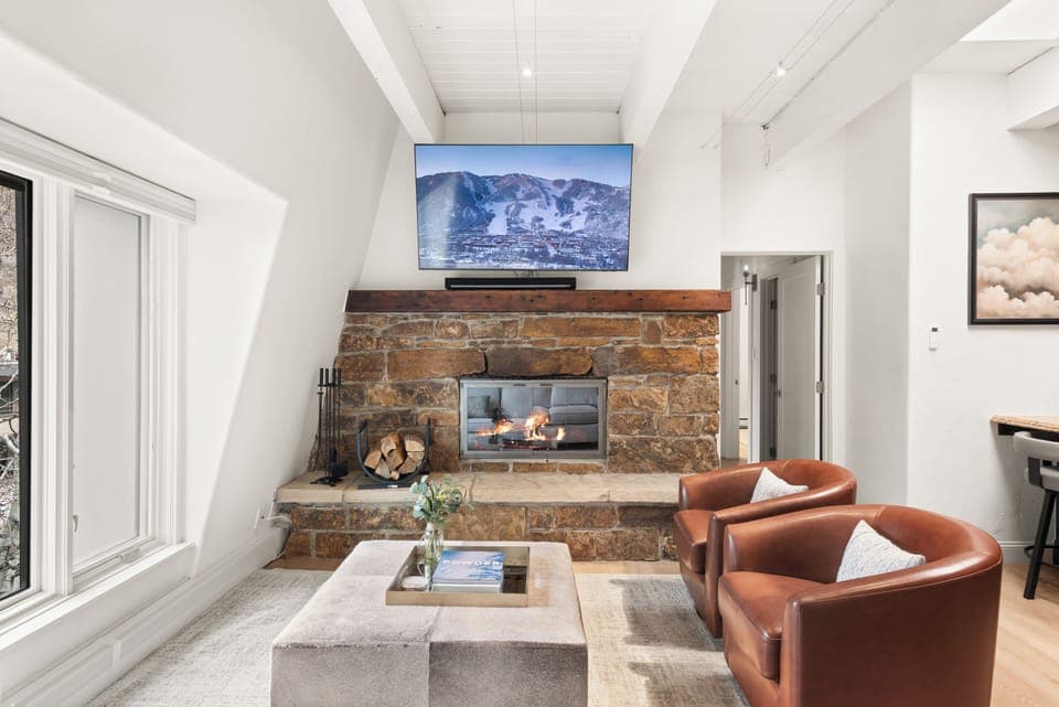 Top-floor sanctuary at Chateau Dumont. This living room features a 65" smart TV with Xfinity cable and Roku Streaming, queen-sized pull out couch, wood-burning fireplace, views of Smuggler and Red Mountain.