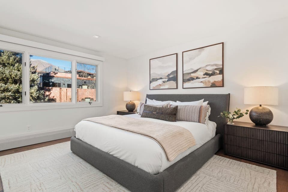Spacious primary bedroom featuring a king-sized bed, TV with Roku streaming services and cable, ample storage, views of Red Mountain, and ensuite bathroom.