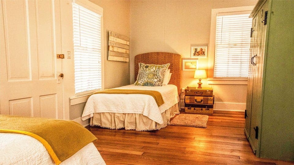 Twin bedroom #2. - Twin Bedroom #2 features an attached half bath with a stand-up shower and a vintage armoire for storage. One of the room’s most charming touches is the nightstand crafted from stacked vintage suitcases.