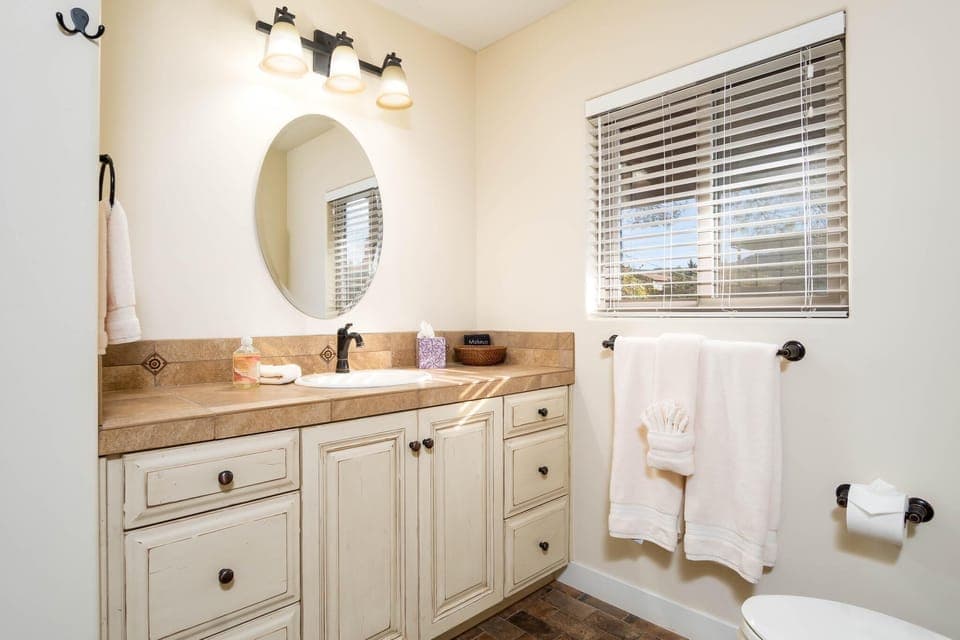 A large remodeled bathroom with shampoo, conditioner, and body soap.
