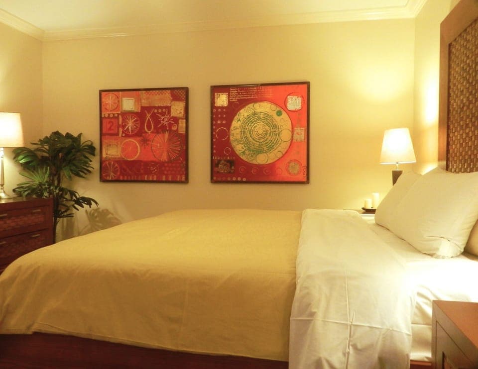 Master bedroom with local art, comfy bedding and ensuite double rain shower bath